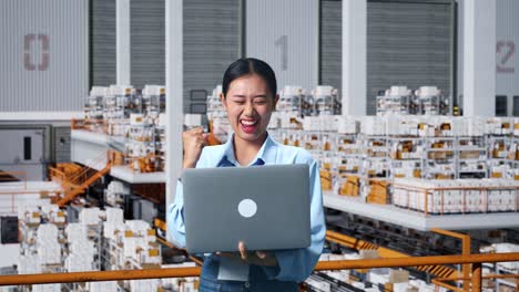 feliz mujer de negocios asiática celebrando usando una computadora portátil en el almacén