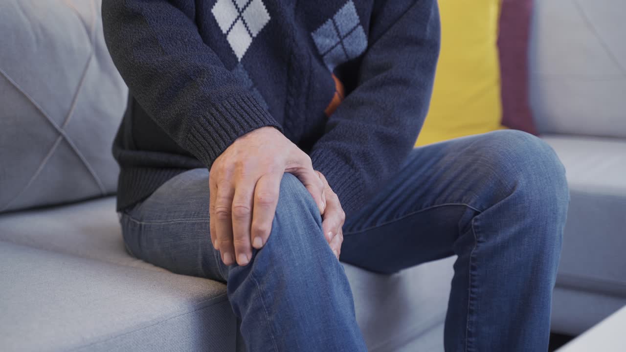 Old man with pains rubbing his legs.