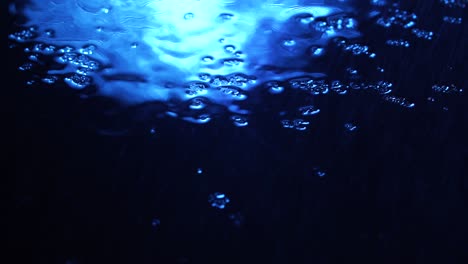 footage of water drops on dark blue glass