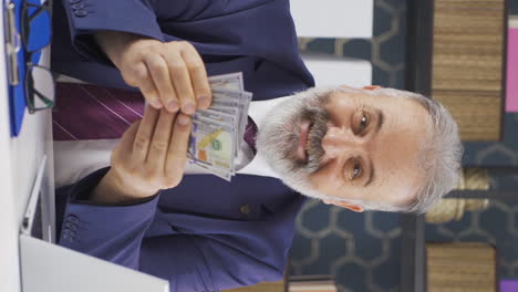 vertical video of old businessman counting money looking at camera.