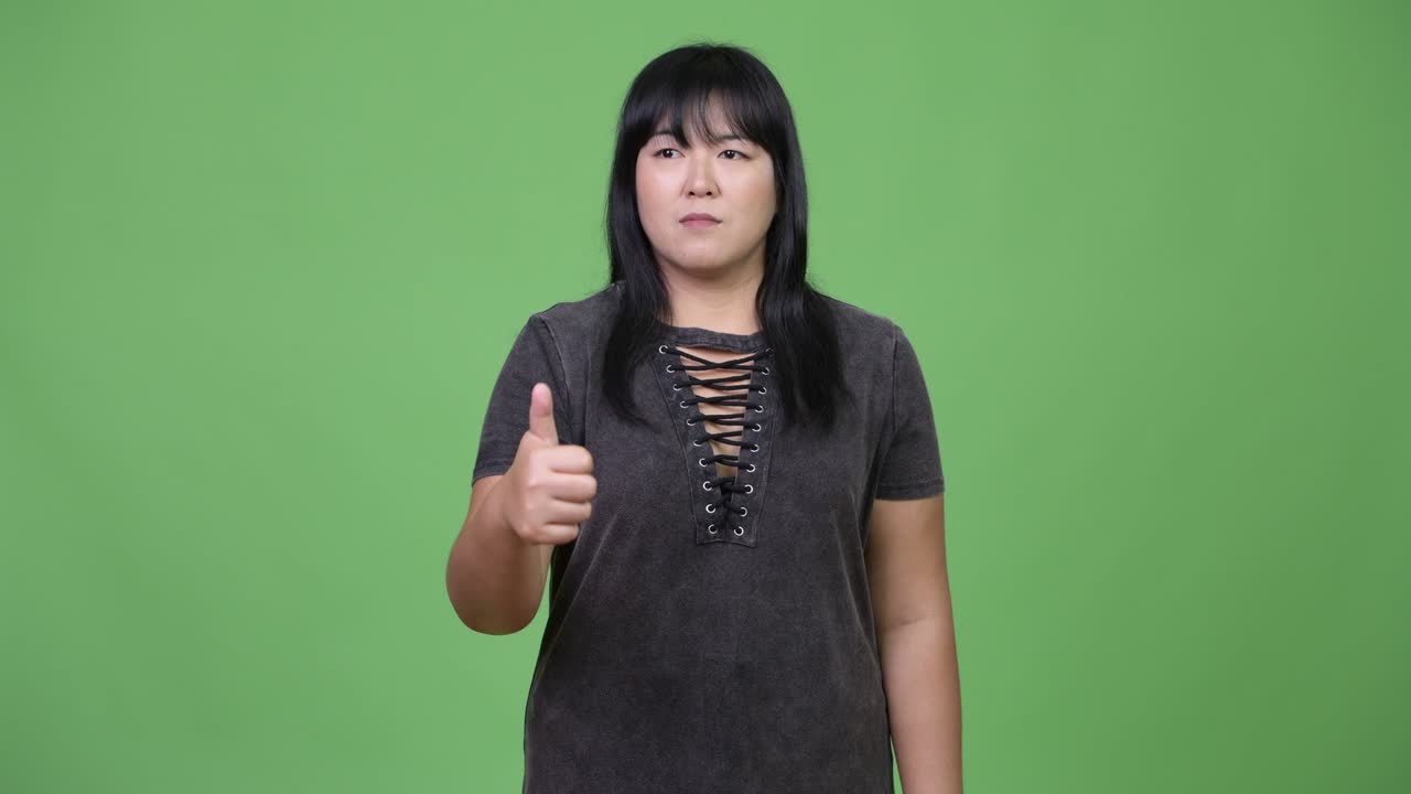 Beautiful overweight Asian woman giving thumbs up