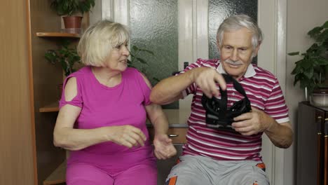 Grandfather-and-grandmother-with-VR-headset-helmet-play-games,-watch-virtual-reality-3D-360-video
