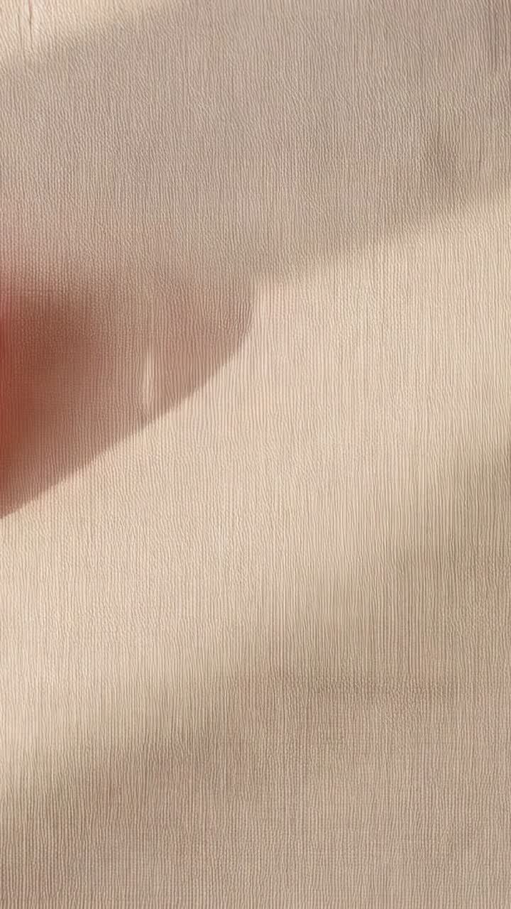 Vertical video: Moving fingertip from left with red nail over cream wall casting shadow, copy space