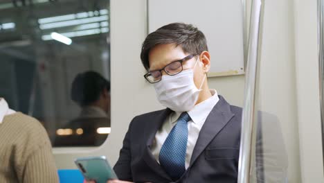 traveler wearing face mask while using mobile phone on public train