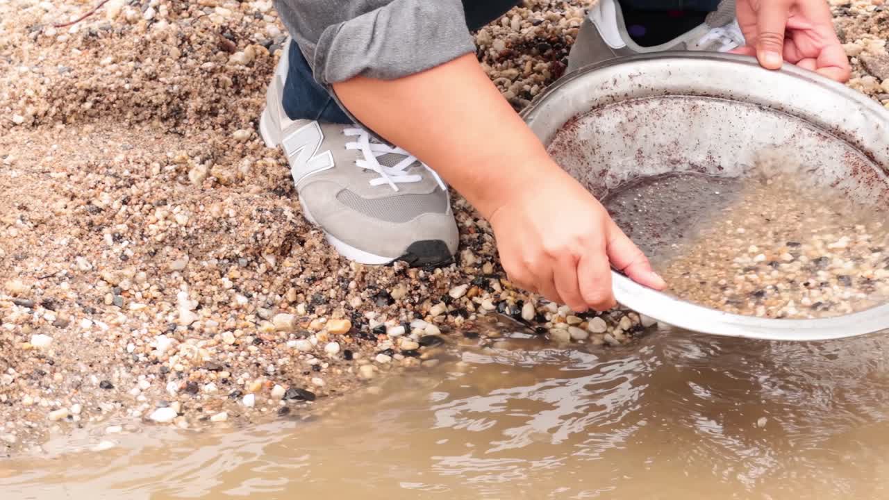 persona buscando oro en aguas fangosas