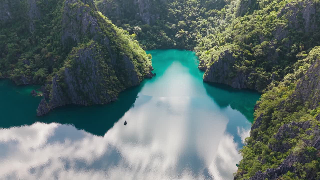 Tranquilla laguna color smeraldo che riflette le nuvole tra spettacolari scogliere calcaree ricoperte di giungla.