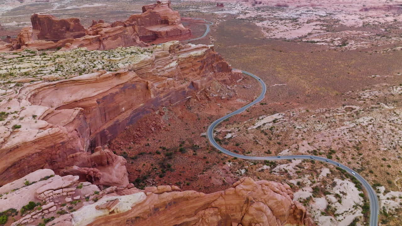 Curvy road going round the majestic rocks of Utah National park. Amazing canyons and deserted lands from aerial perspective.