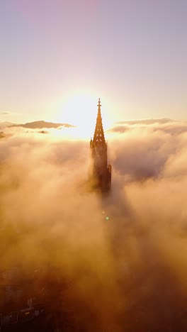 vertical version of dronefootage of the münster church in bern, the capital city in switzerland during a fog sunrise.