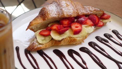 delicious croissant with strawberries, banana and chocolate sauce