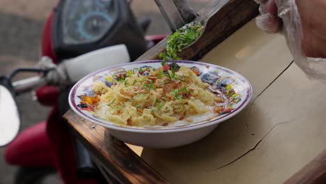 mano con guantes de plástico salpicaduras de cebolla sobre el plato de avena indonesio