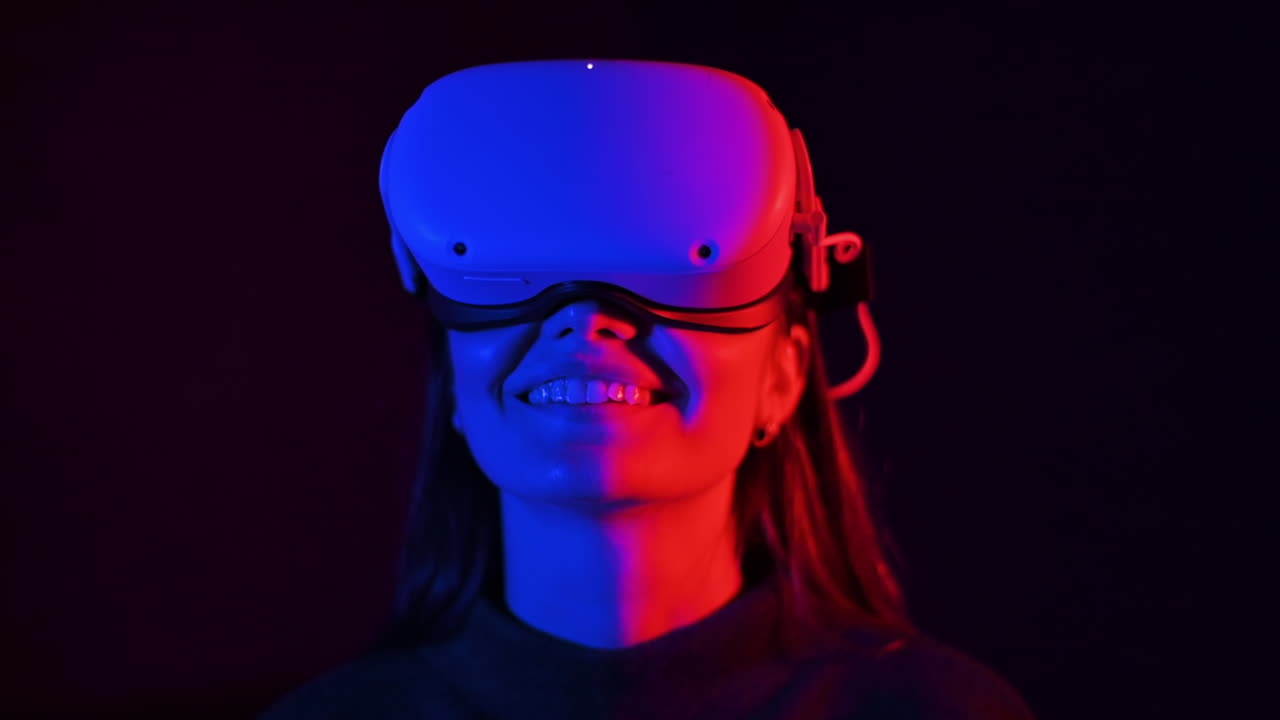 A young woman is excited while wearing VR glasses, Red and blue illumination. Slow motion