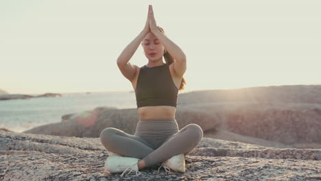 woman, yoga and meditation on rock at the beach