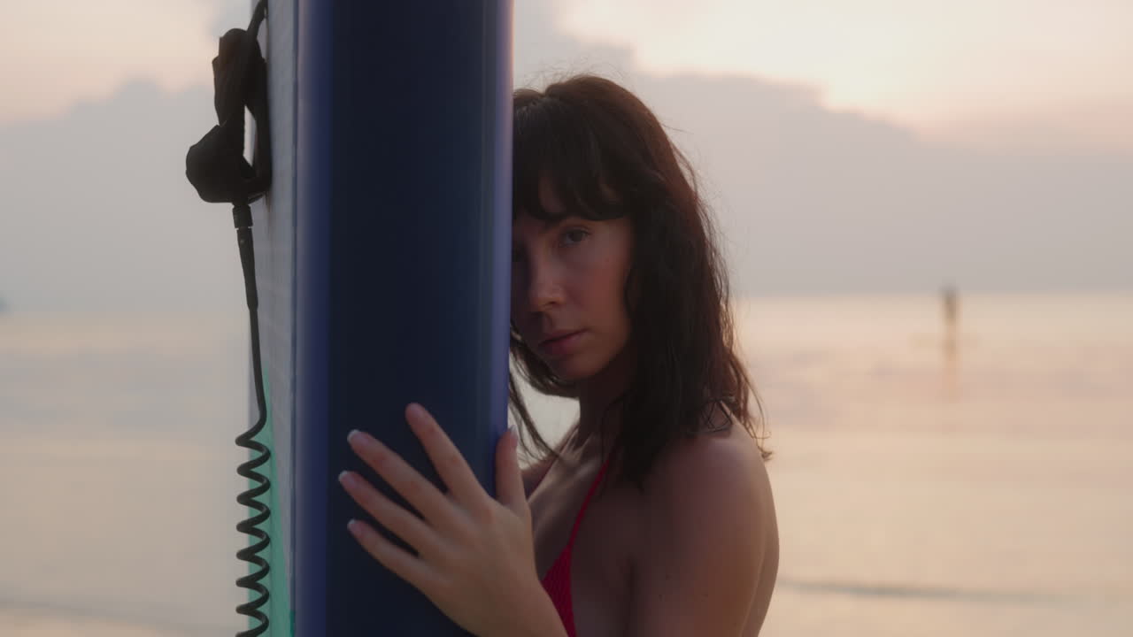 Young Woman Posing with Surfboard on the Beach at Sunset