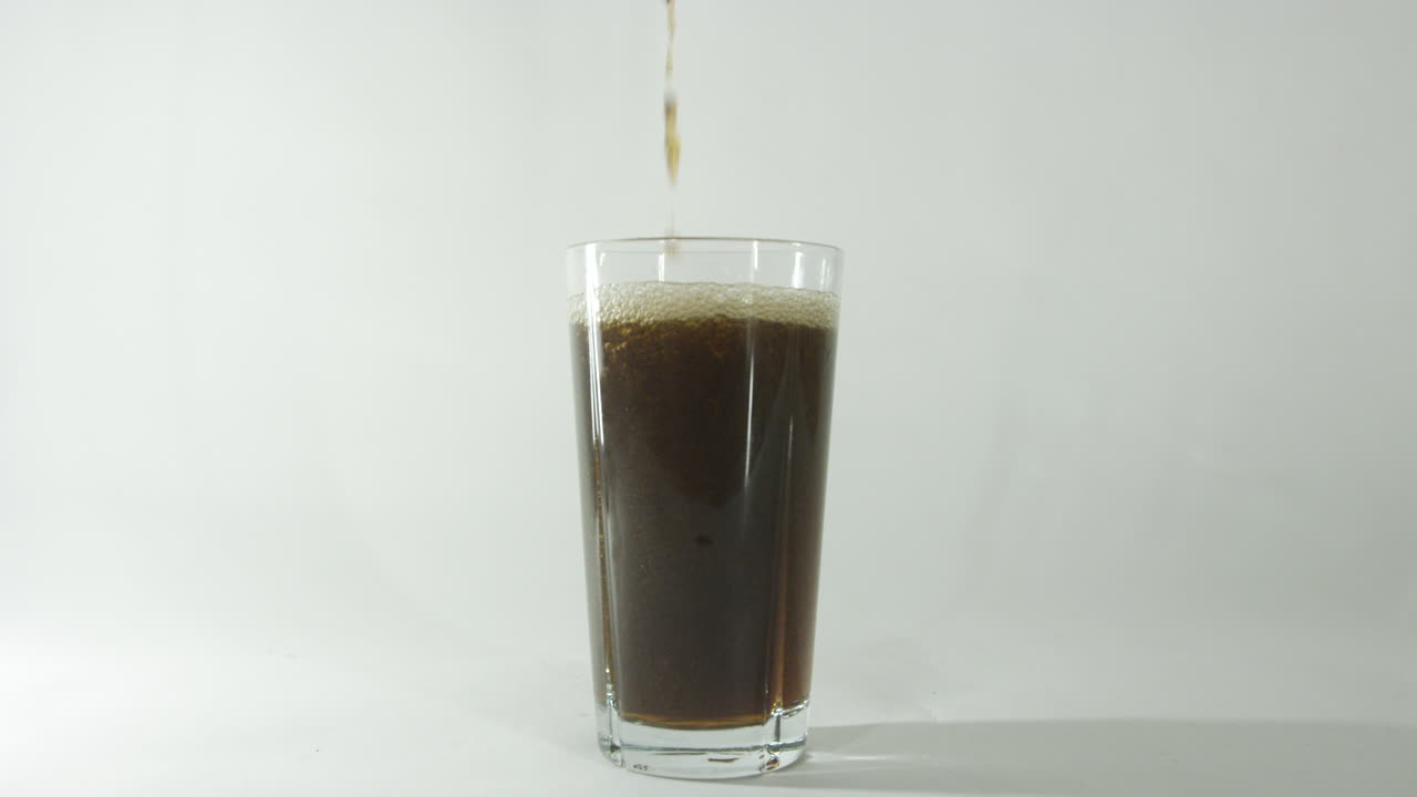 Bevanda cola versata in un bicchiere su sfondo chiaro