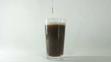 bebida de cola que se vierte en un vaso con un fondo claro