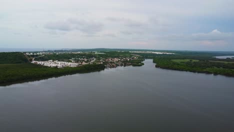 Aerial-drone-forward-moving-shot-over-resort-buildings-alongside-Mandinga-Lagoon-mangrove-area,-Veracruz-in-Mexico-during-kayak-trip