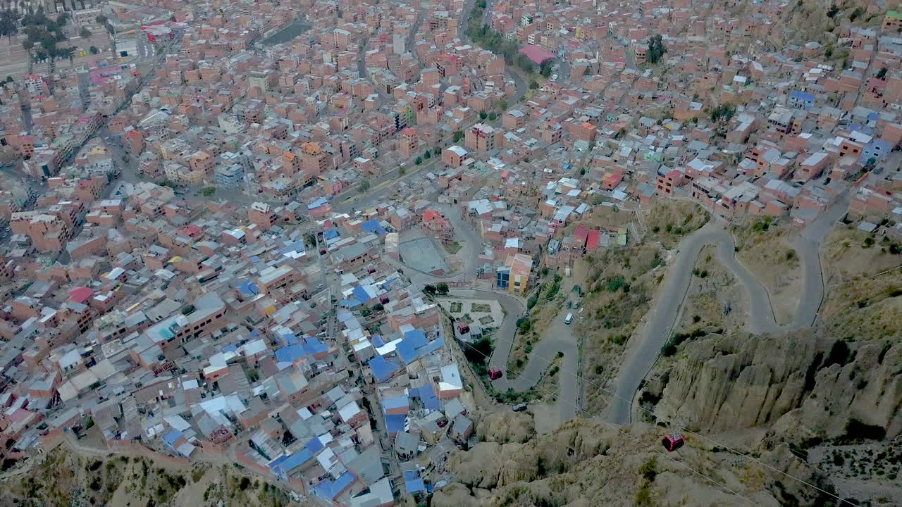las carreteras de alfileres salpican el paisaje urbano en este pintoresco avión no tripulado inclinado hacia abajo vista de la paz, bolivia