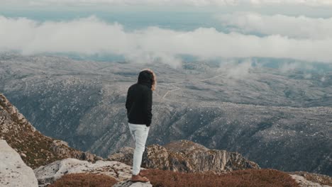 Mann-Steht-Auf-Einem-Felsen-Und-Genießt-Die-Herrliche-Landschaft-Aus-Bergen-Und-Wolken-Mit-Nebel