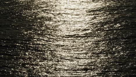 glistening sea surface at dusk in cascais resort town near lisbon, portugal. tilt-up shot