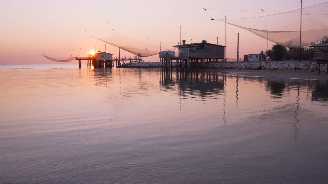 toma de paisaje de cabañas de pesca en el río al amanecer con la típica máquina de pesca italiana, llamada "trabucco",lido di dante, fiumi uniti ravenna cerca del valle de comacchio