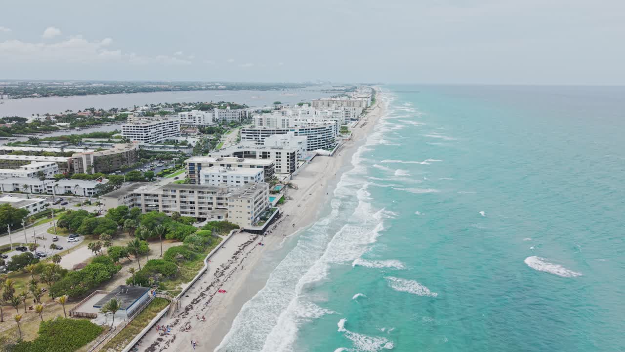 Establishing drone shot of beach and hotels next to Atlantic Ocean with cloudy weather during the day in West Palm Beach, Florida, USA