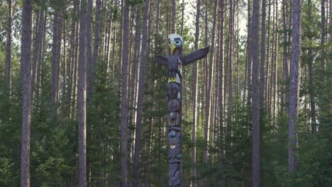 un tótem indígena se encuentra entre un bosque, parque provincial de algonquin