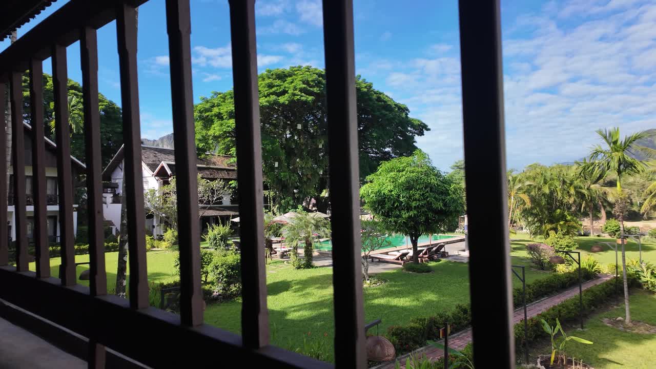 Relaxing view from a resort balcony overlooking a tropical garden and swimming pool
