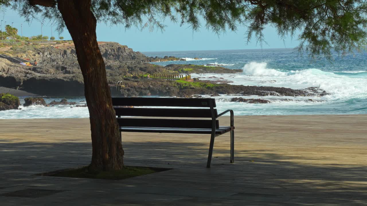 Odlehlá lavička s výhledem na oceán shlížející na vlny na Tenerife: Chvíle k zamyšlení o samotě.
