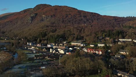 Beautiful-Autumn-Hillside-at-Craigmore-with-Aberfoyle-Village-Nestled-Amongst-the-Forest-Autumn-Trees-in-Scotland