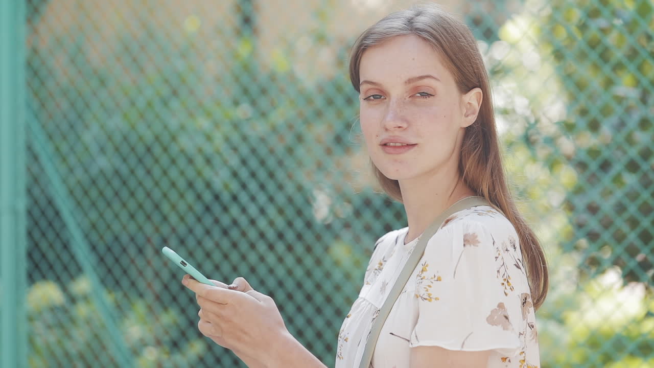 スマートフォンから顔を上げて笑顔を見せる若い女性
