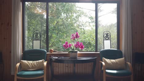 una foto tranquila y vacía con dos asientos ornamentados de estilo chino frente a una gran ventana adornada con una intrincada decoración china