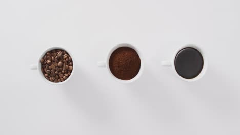 Video-of-three-white-cups-of-coffee-and-coffee-beans-on-white-background