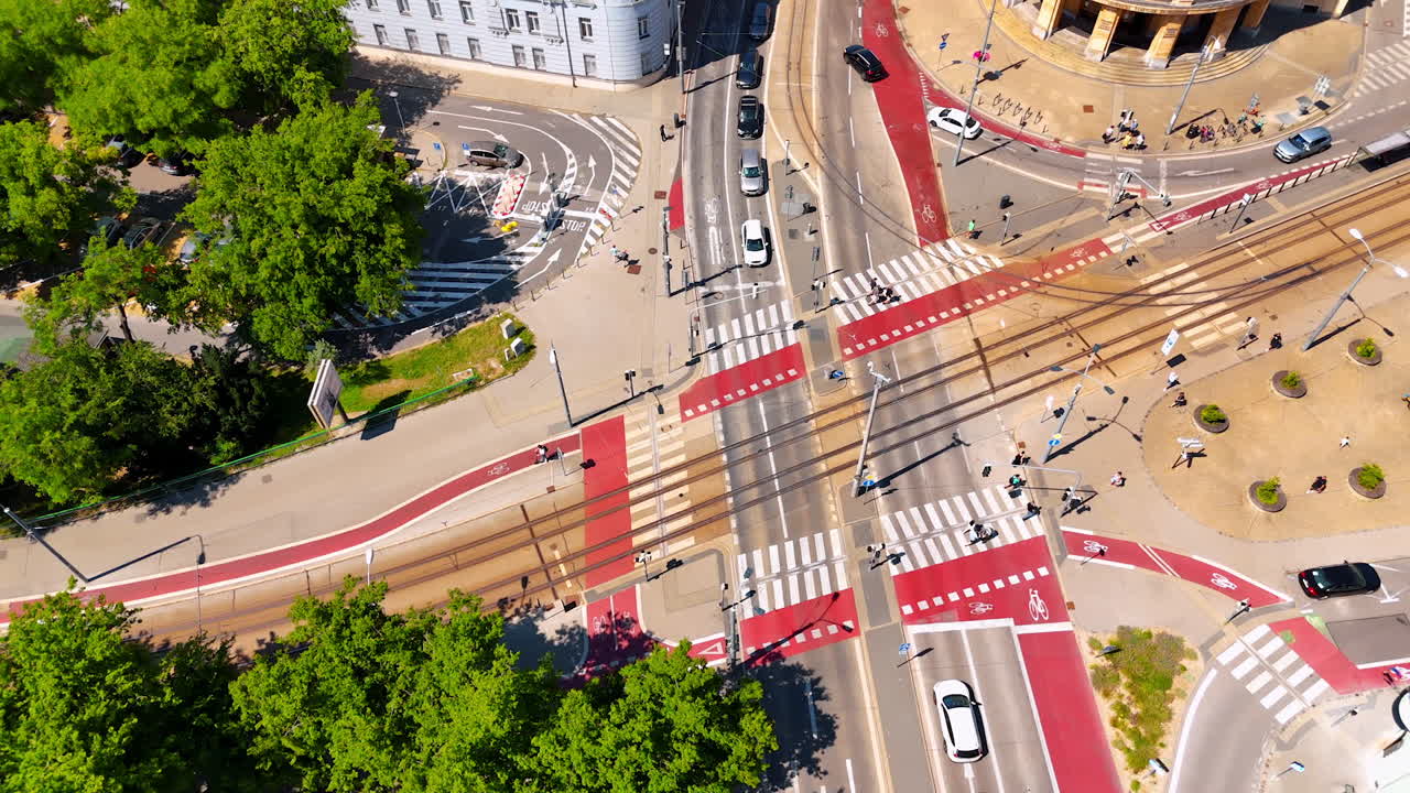 People walk by the crossroads in the city with lush greenery. Drone flight over the street in Bratislava, Slovakia.