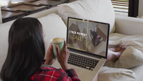 biracial woman using laptop at home for online shopping, slow motion