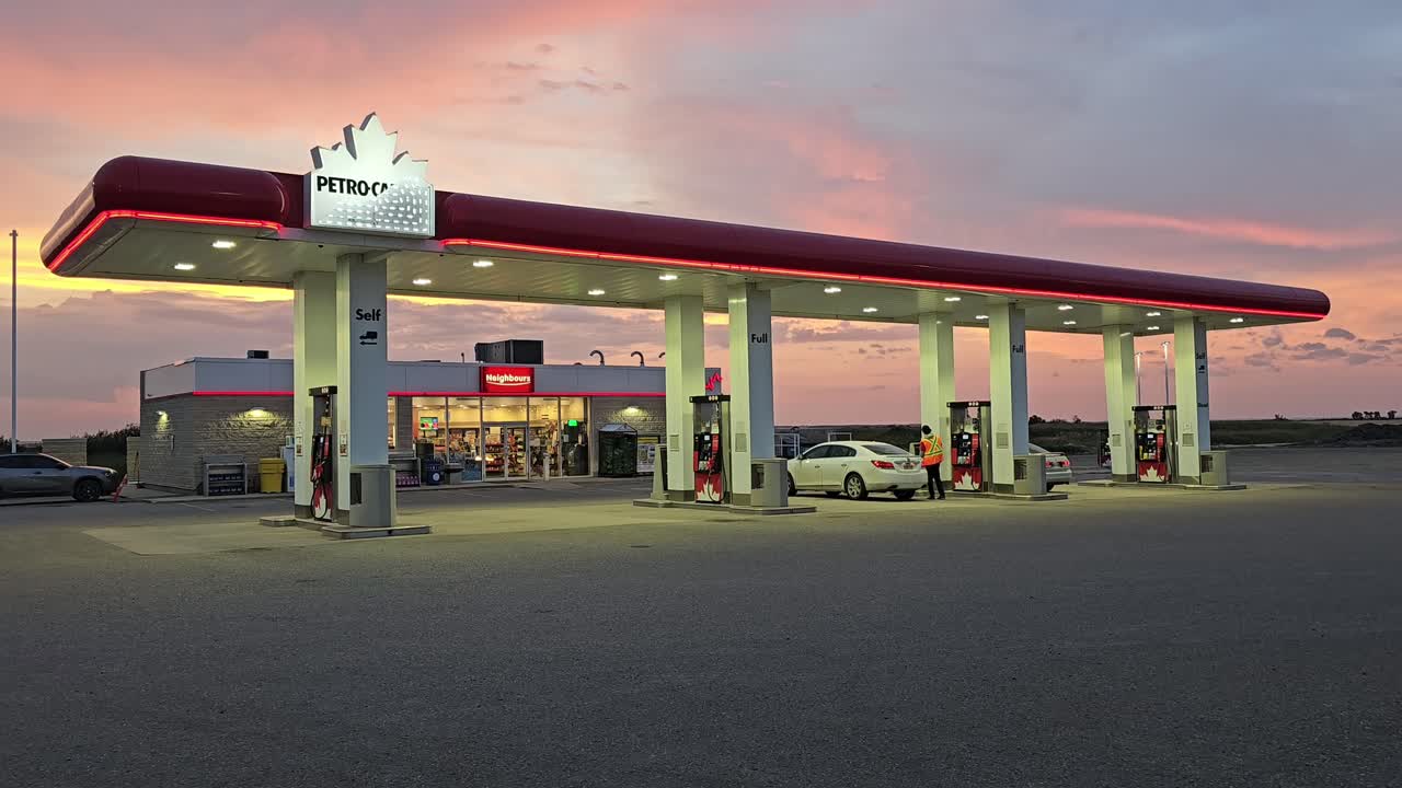 Griswold, Manitoba - Aug 20th 2024: A Petro-Canada gas station glows under a vibrant sunset. Cars fuel up as customers interact with staff.