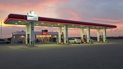 griswold, manitoba - aug 20th 2024: a petro-canada gas station glows under a vibrant sunset. cars fuel up as customers interact with staff.