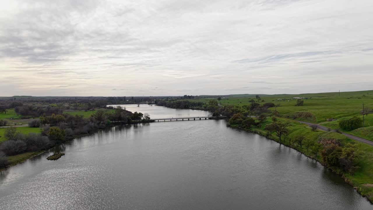 From above, Lake McSwain displays a striking blend of water, stone, and sky, with the winding river feeding the reservoir and rolling hills stretching into the distance.