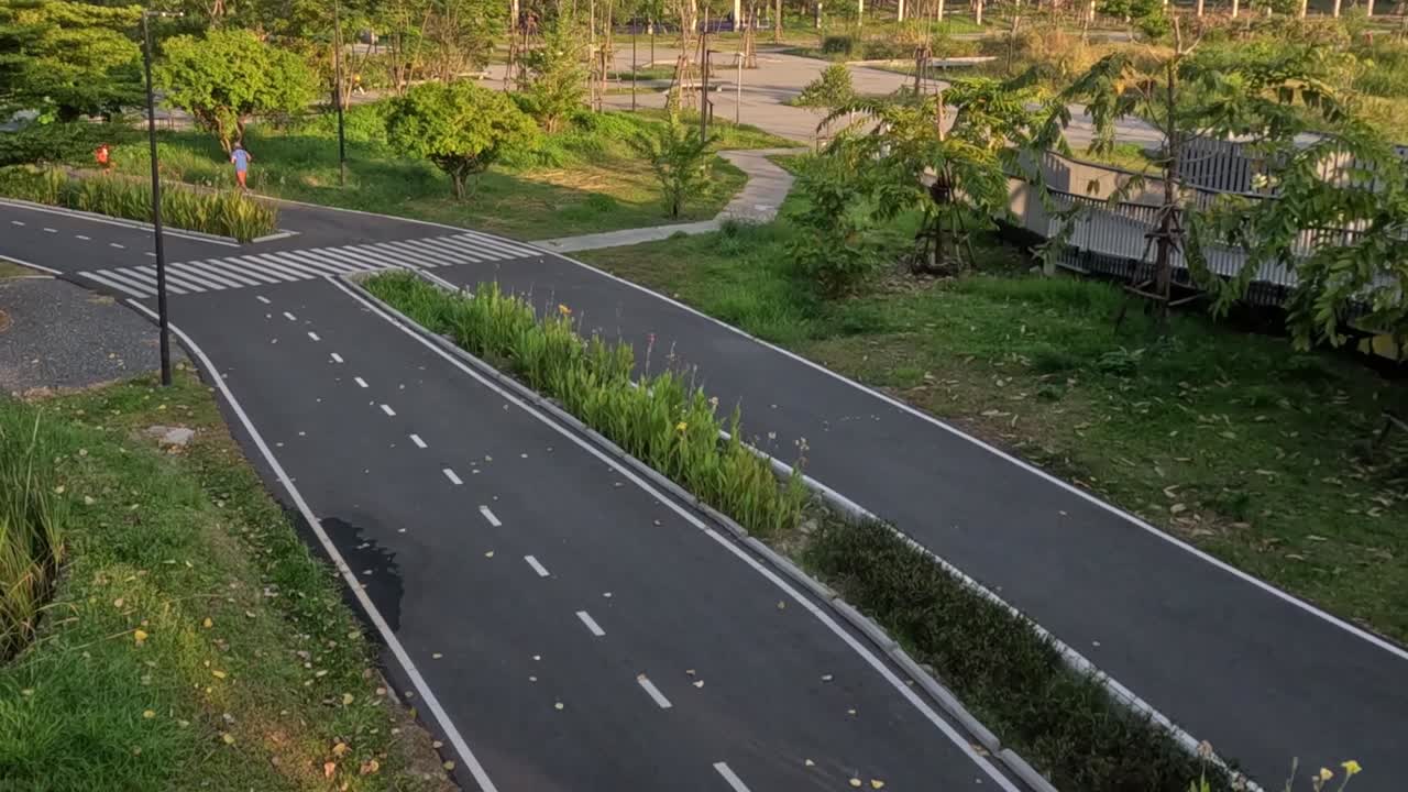 A cyclist rides along a peaceful park pathway surrounded by lush greenery and trees.