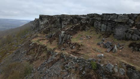 cinematic aerial drone footage over dramatic rock formations and moorland in the peak district, uk