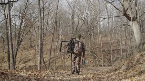Gimbal-following-bowhunter-holding-hunting-equipment-walking-on-forest-path