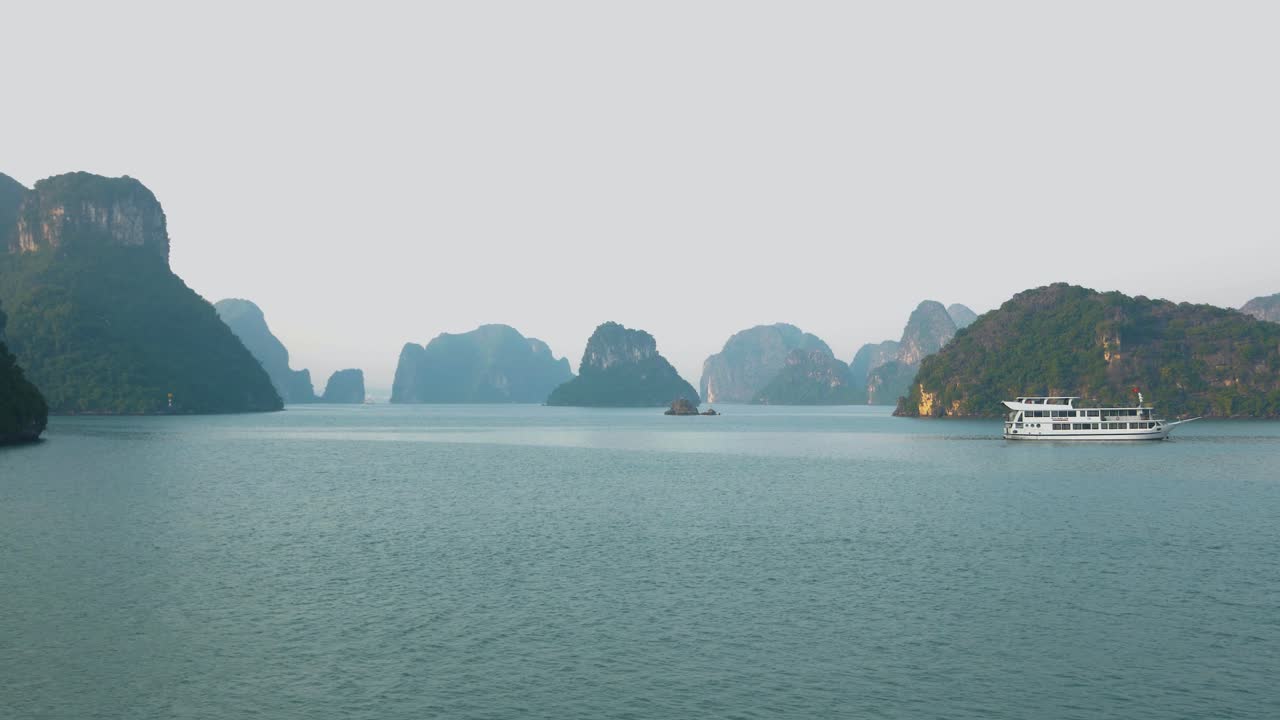 극적인 저녁 풍경: 하롱 만의 바위 석회암 산들 사이에서 크루즈 보트