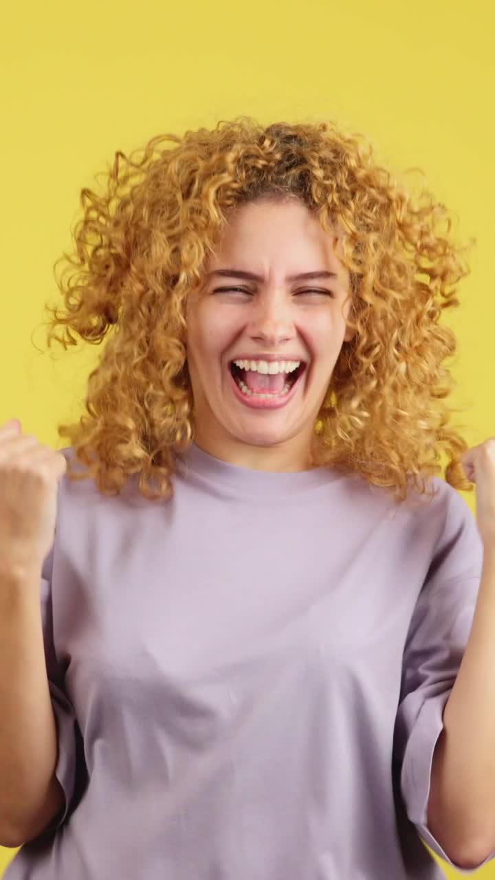 Excited woman screaming or cheering with joy on a yellow background