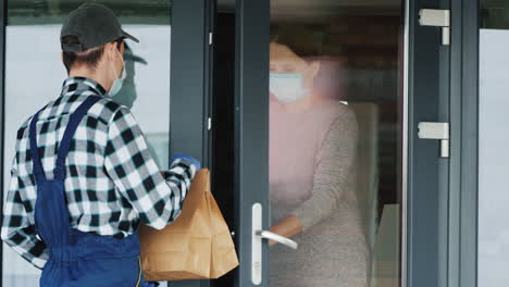 a messenger in a mask and gloves delivers food to the customer's door