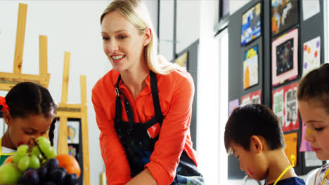 teacher assisting schoolkid in drawing class