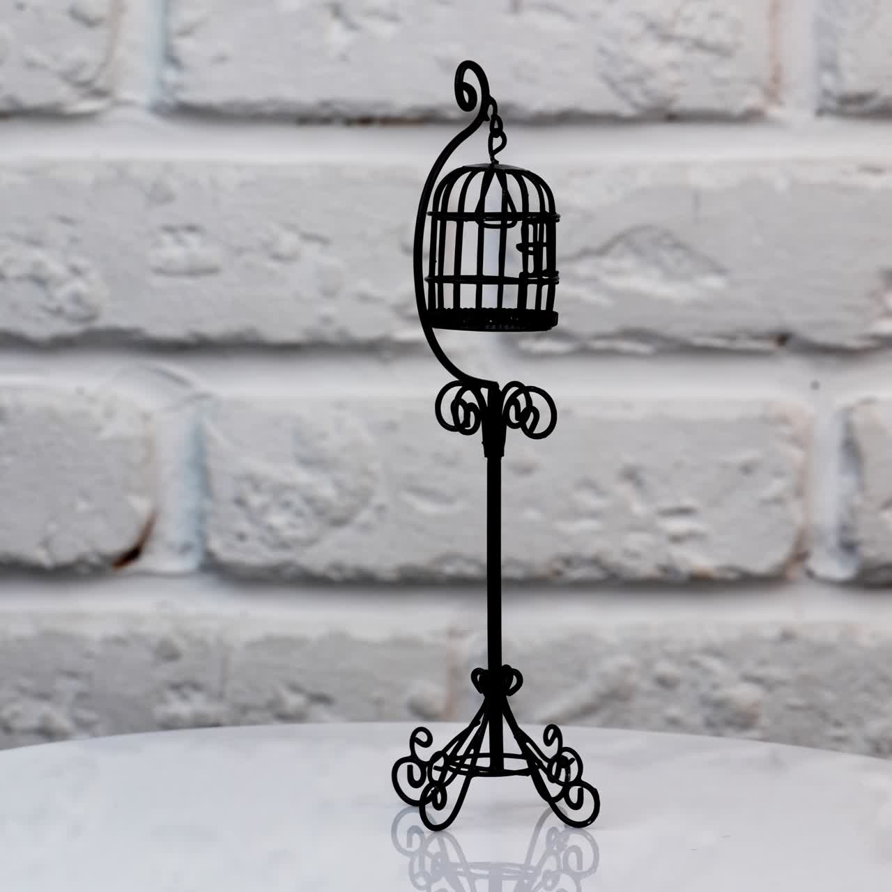 Small black cage for a canary at the rotating table. Fine toy bird cage for the decoration of doll's house. Close up