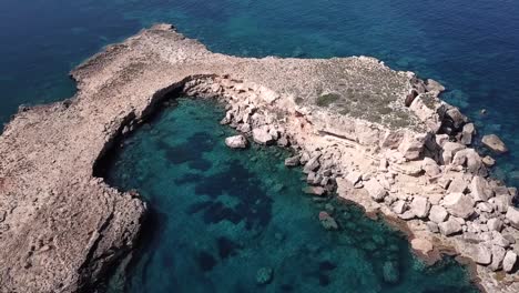 aerial orbit shot of a secret moon-shaped island in the north of ibiza on turquoise waters