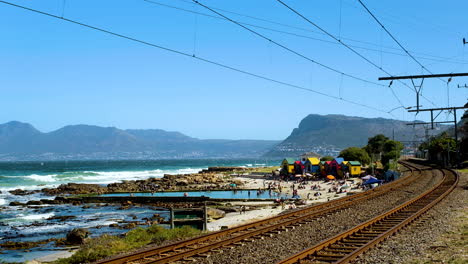 st james beach with colorful bathing boxes next to railroad, muizenberg