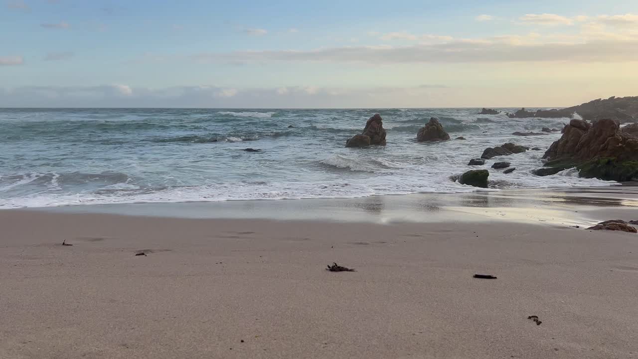 Waves come in and go out on a beach during a beautiful sunset