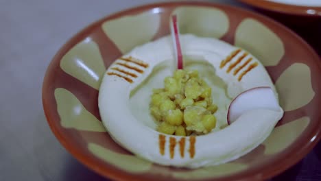 decorating fresh hummus dish with radish all around and cumin