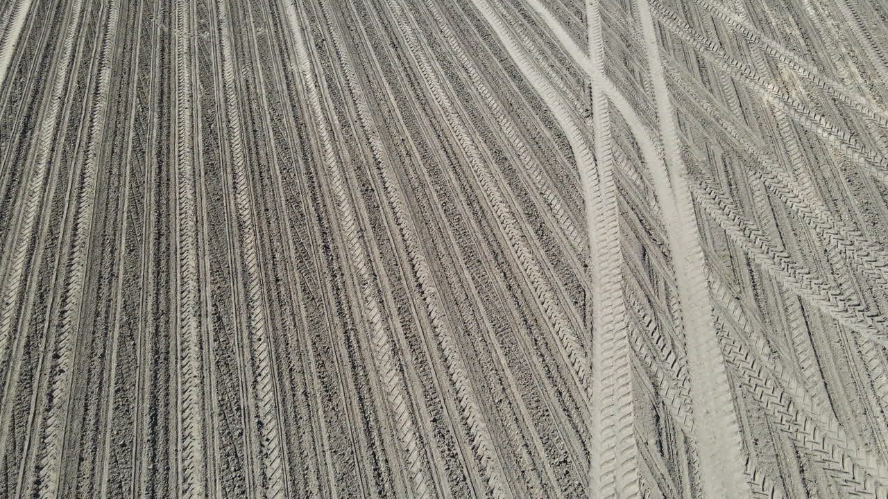 Drone shot of sandy field with tracks ready to be used for growing.